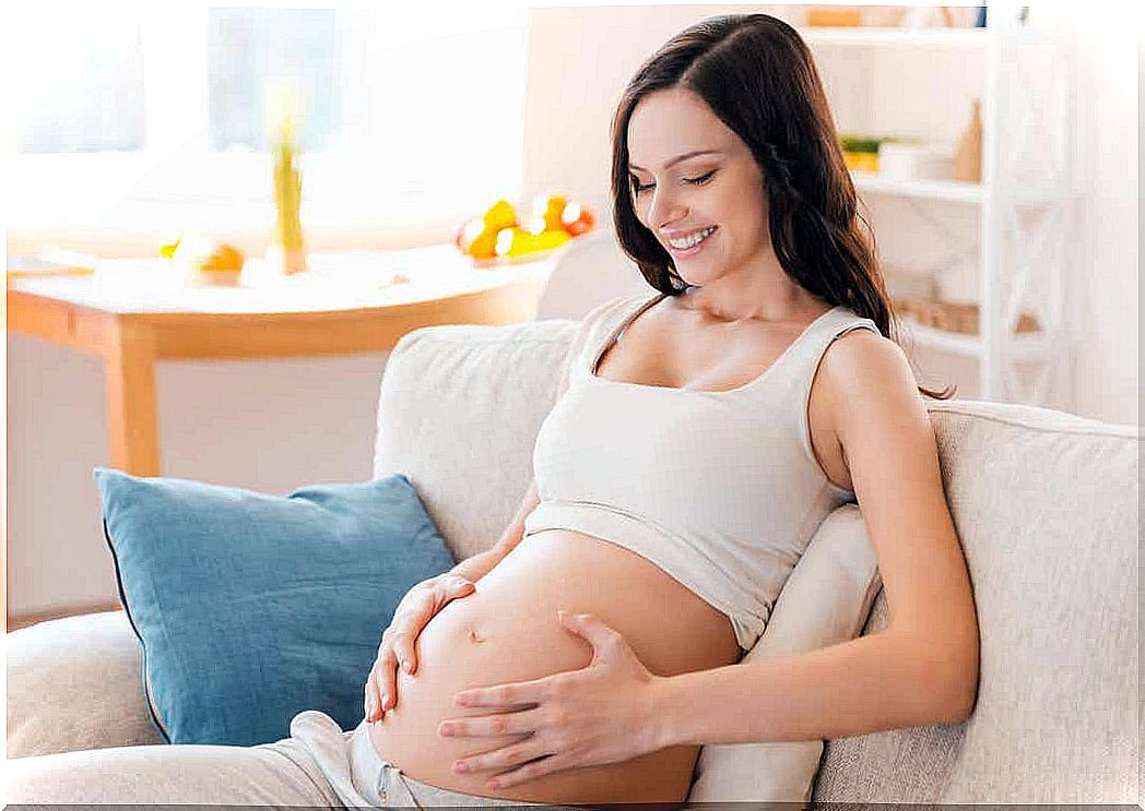 A pregnant woman with her hands on her bare belly.