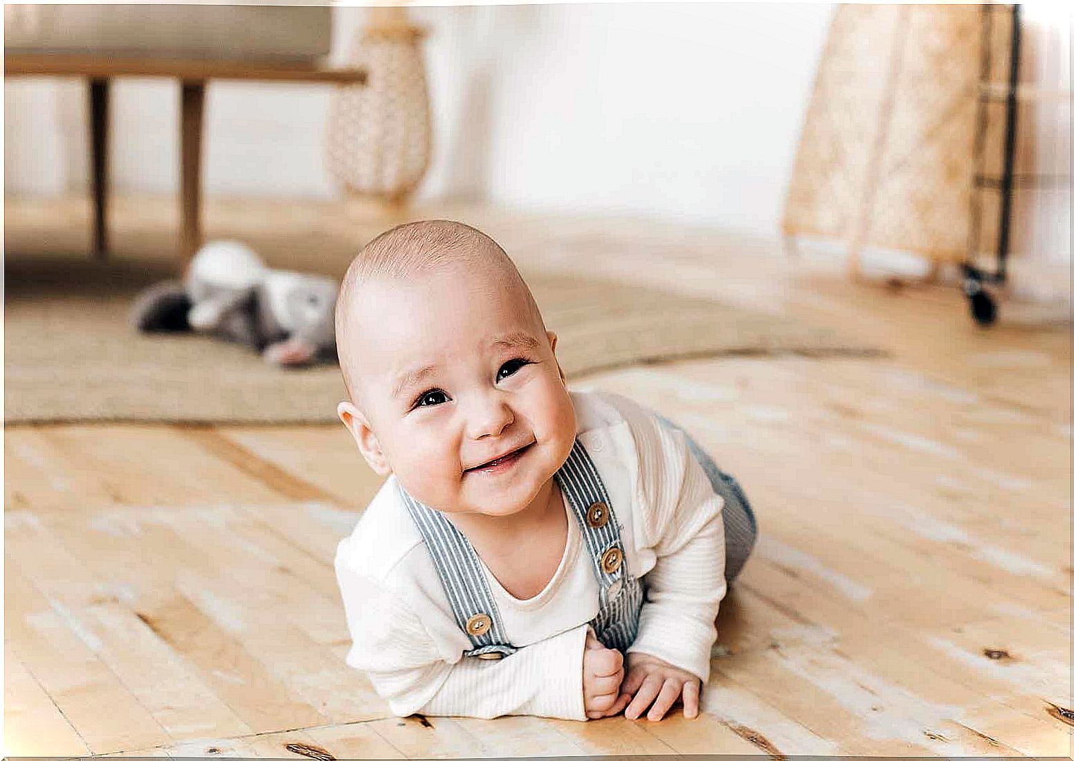 A smiling baby lying on his stomach with his head up.