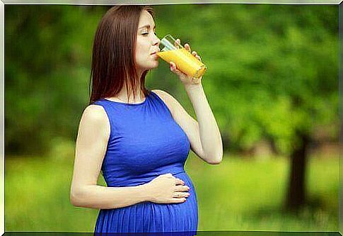 pregnant woman drinking orange juice outside