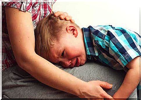 A little boy crying on his mother's lap.