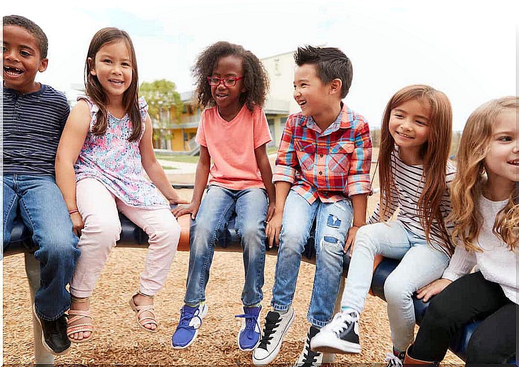 A diverse group of children sitting on playground equipment.