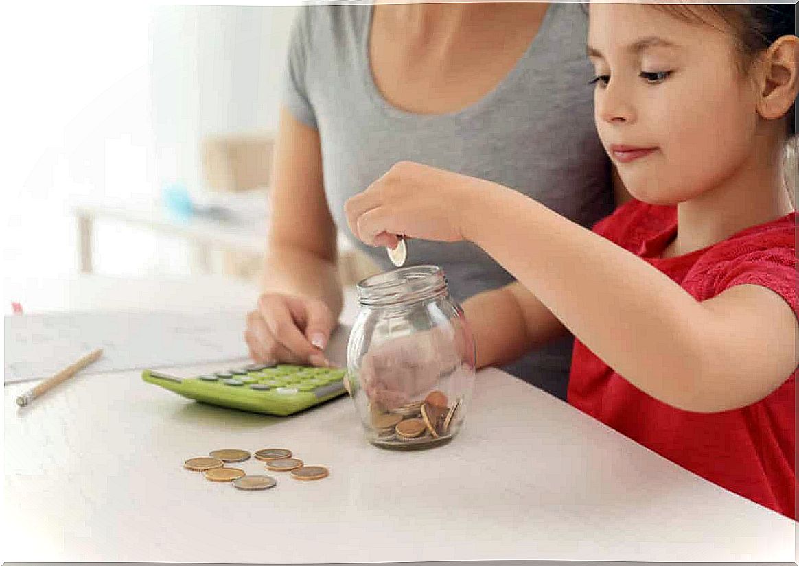 A mother uses a calculator while her young daughter drops loose change into a jar.