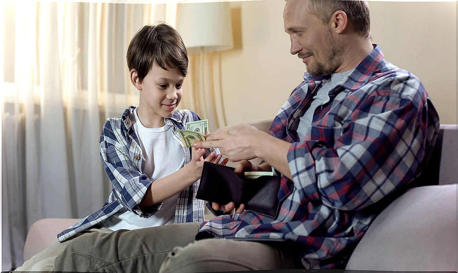 A father giving money from his wallet to his young son.