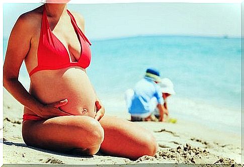 Pregnant woman sitting on the beach