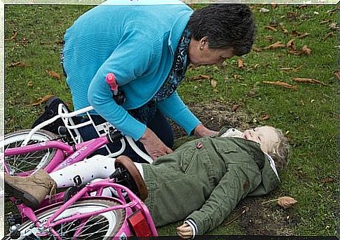 Girl lies on the ground under bicycle