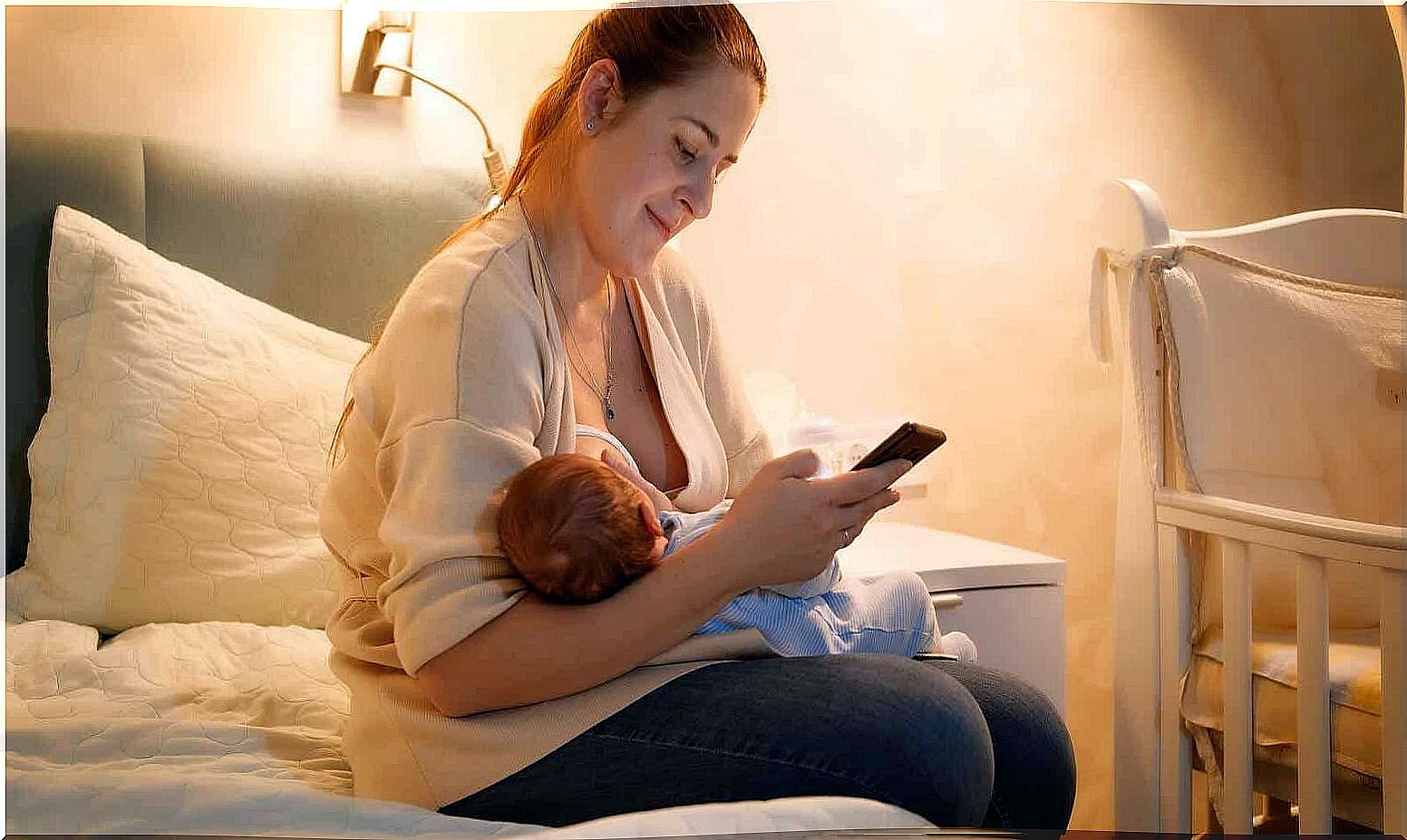 Mother breastfeeds her baby while consulting some apps.