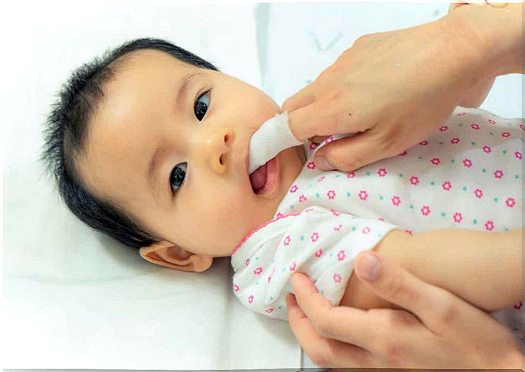 A mother brushing her baby's gums.