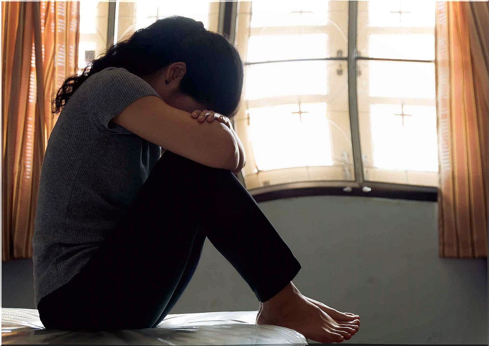 A woman with postpartum depression crying on her bed.