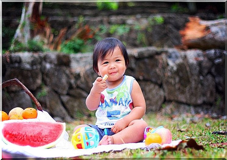 Baby eats fruit while playing