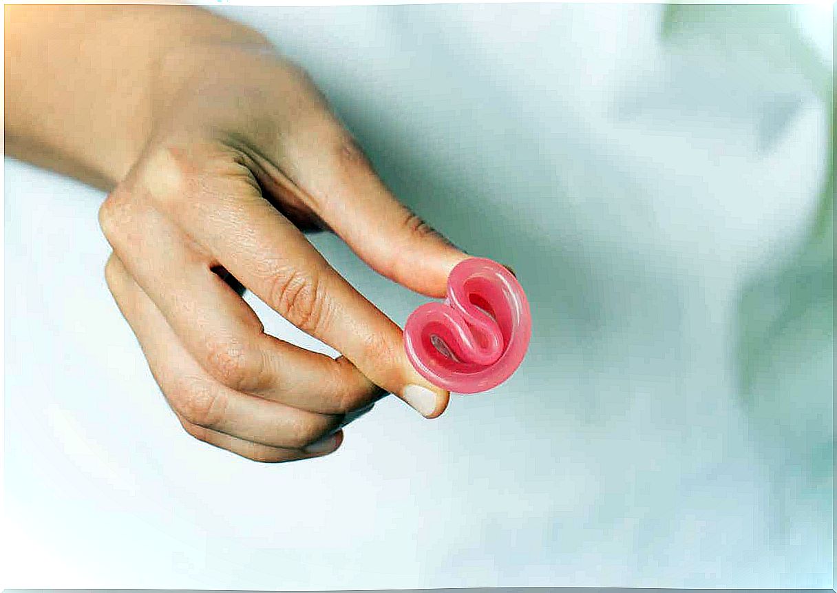 A woman holding a folded menstrual cup between her fingers.