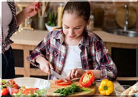 Child helps cook by cutting vegetables