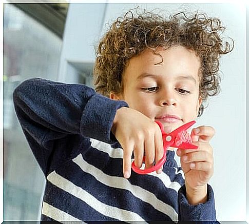 Boy with curls and red scissors