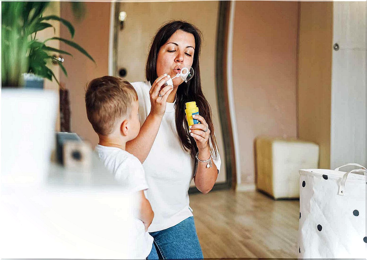 A mother blowing bubbles with her toddler son.