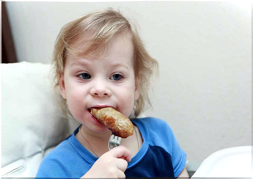 A child biting into a sausage.